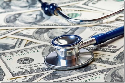 stethescope laying on top a pile of one hundred dollar bills