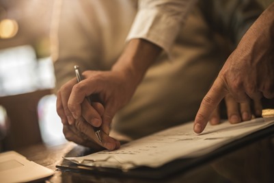 Unrecognizable senior signing a contract with help of financial advisor.