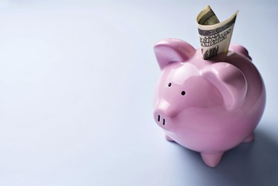 Pink piggy bank with a dollar bill in the slot