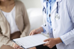 Doctor holding a clipboard asking a patient questions